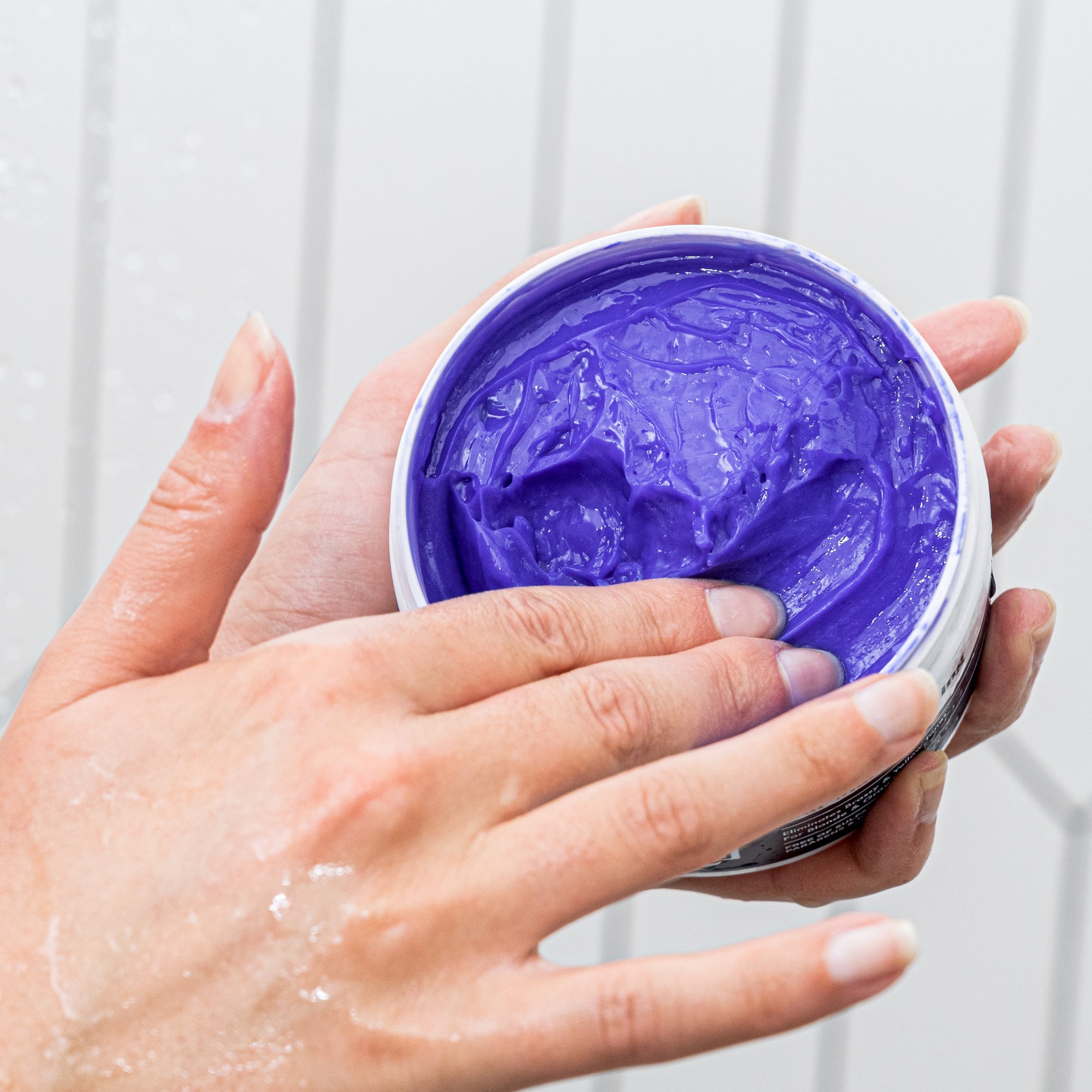 Herbalosophy Color Perfecting Hair Mask jar open with purple cream being scooped out by hand