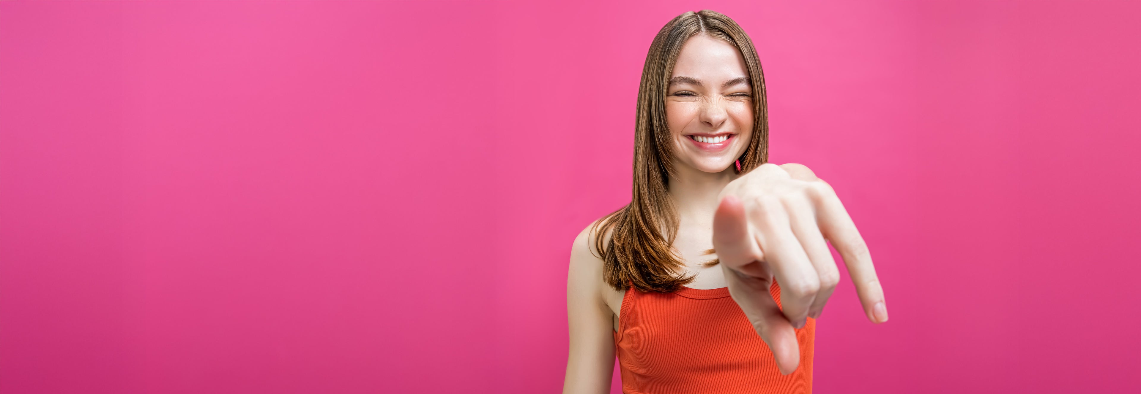 a happy brunette gen z model with stylish hair pointing at the camera.