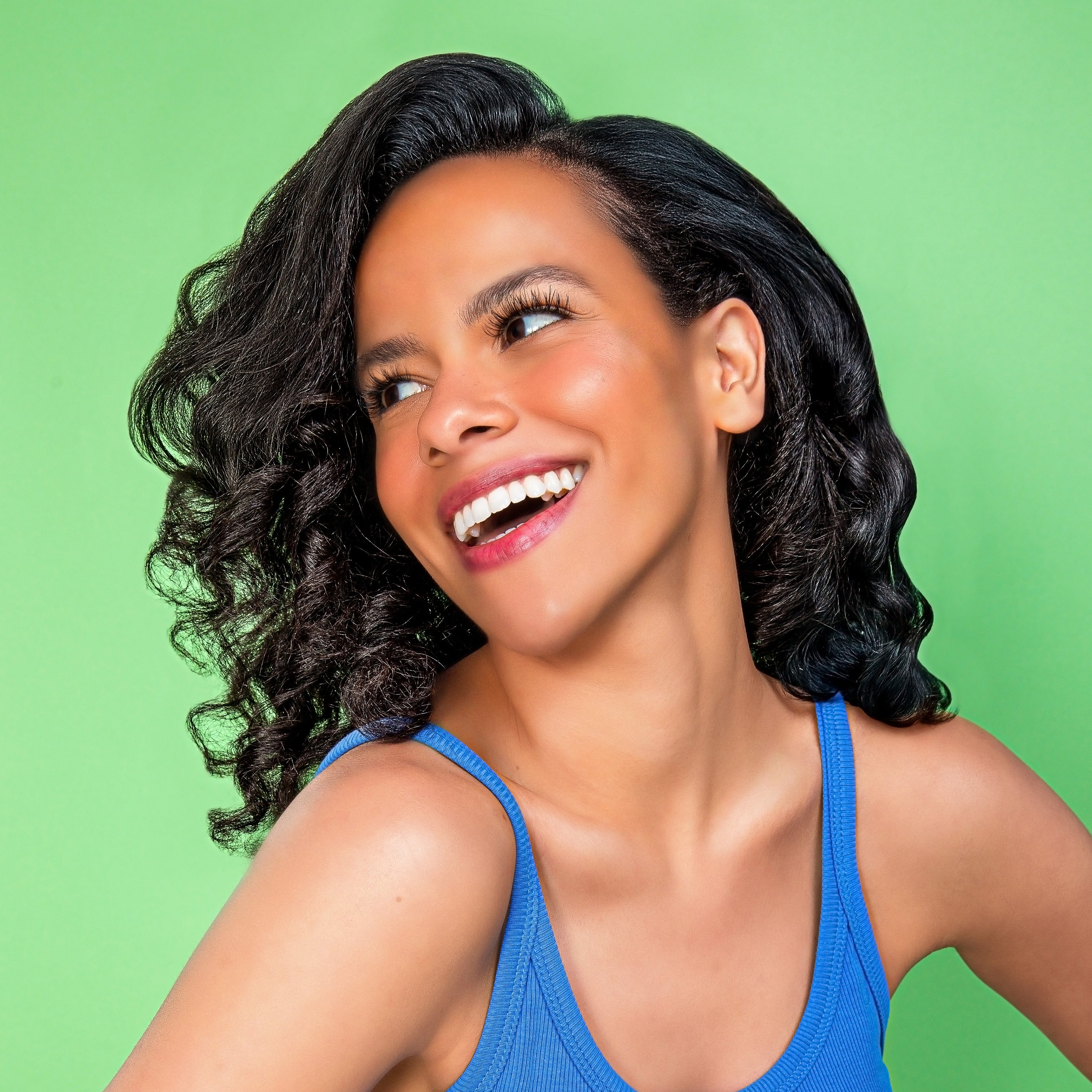 a smiling curly, black-haired gen z model looking left