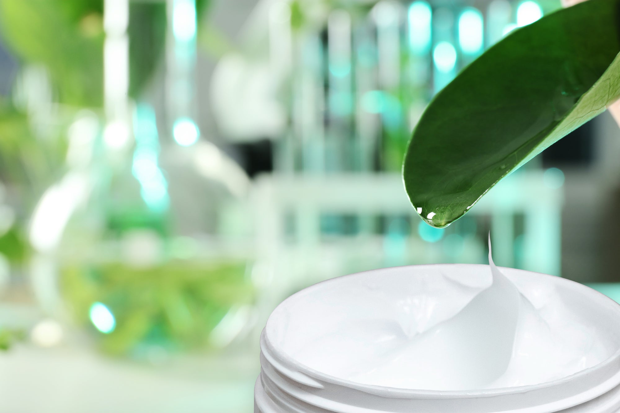 large leaf above jar of creamy hair product with leaves and science beakers in background