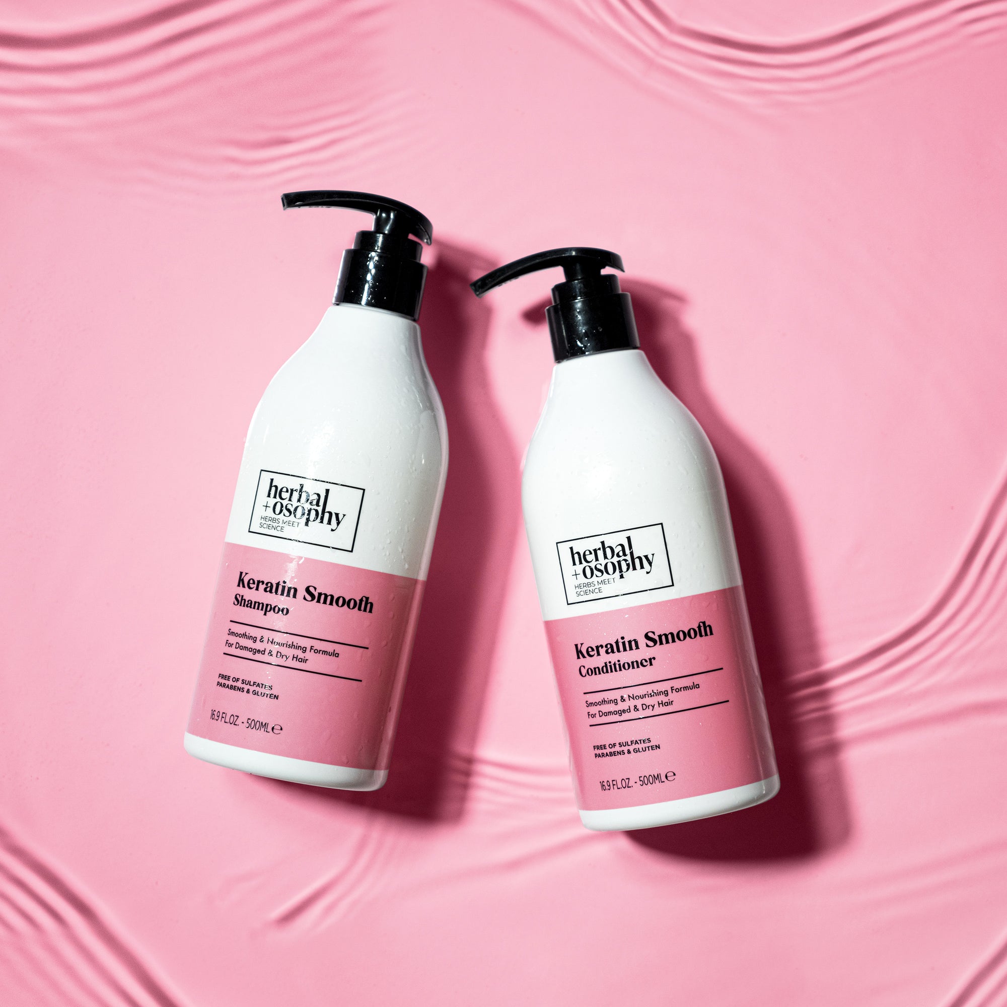 Herbalosophy Keratin Smooth Shampoo and Conditioner bottles in pink rippling water