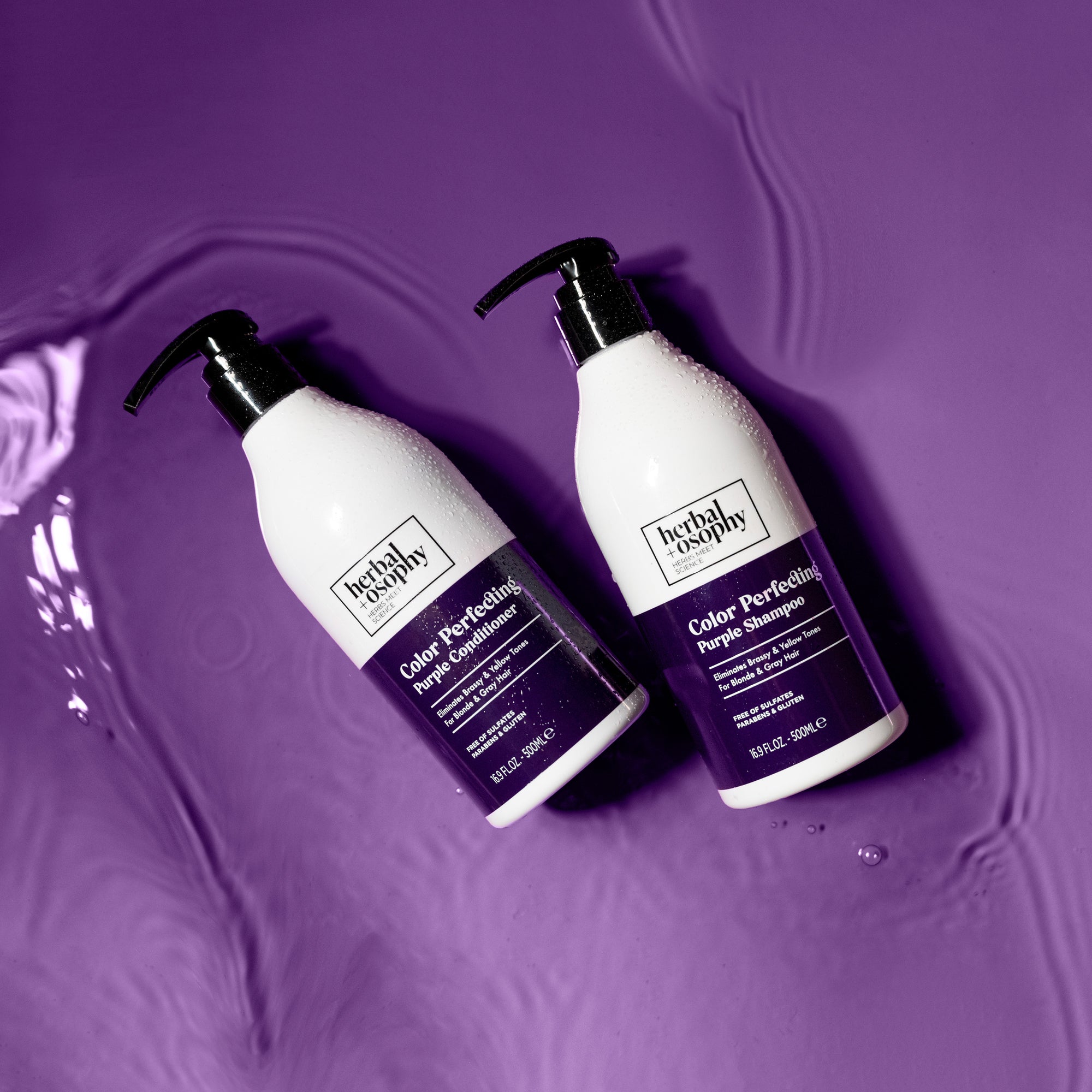 Herbalosophy Color Perfecting Purple Shampoo and Conditioner bottles in rippling purple water