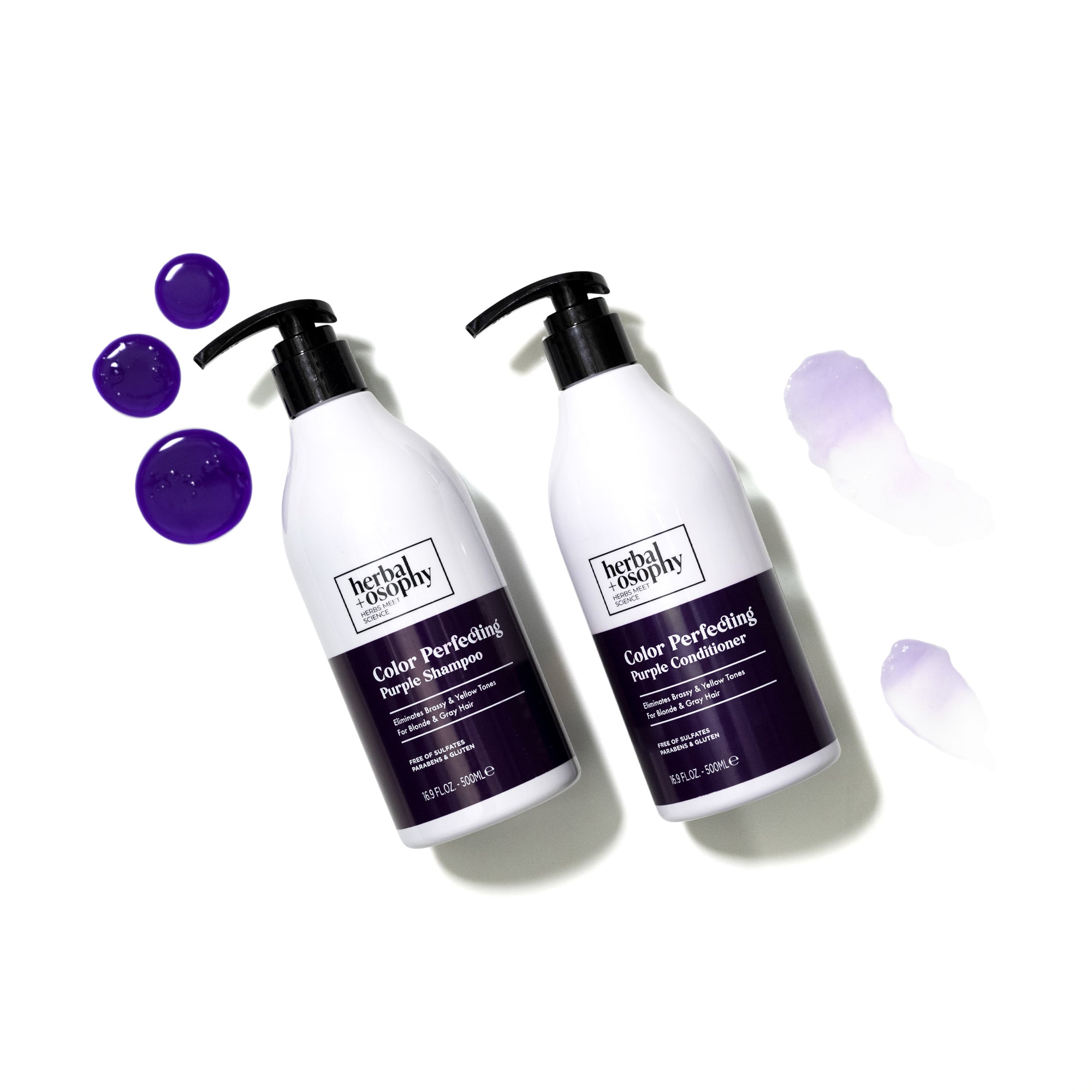 Herbalosophy Color Perfecting Purple shampoo and conditioner on white background with purple drops and smears of product next to them